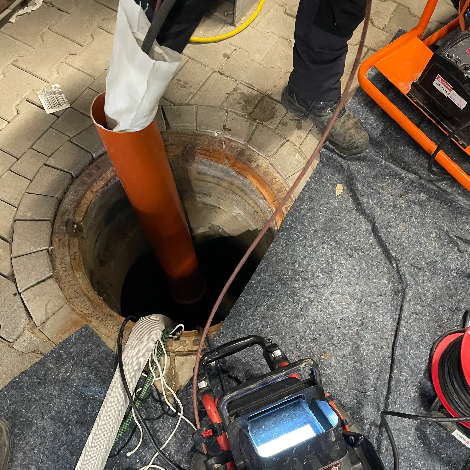 Einzug des Schlauchliners über den geöffneten Schacht in einer gepflasterten Einfahrt